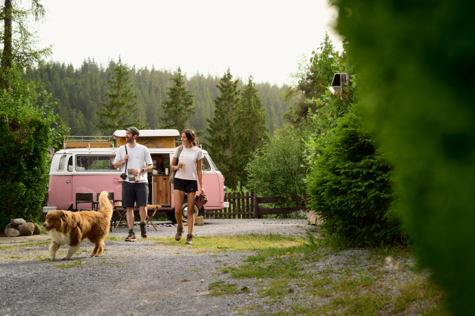 Paar mit Hund vor Campervan auf dem TCS Camping Flims