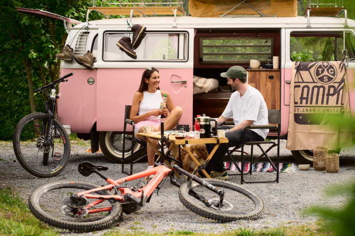 TCS Camping Flims – am Rand des Flimser Grosswaldes gelegen, mit direktem Zugang zum Wander- und Bikeparadies der Region Flims Laax Falera (Foto: © Nicholas Iliano) Paar vor Campervan mit Fahrrädern beim TCS Camping Flims