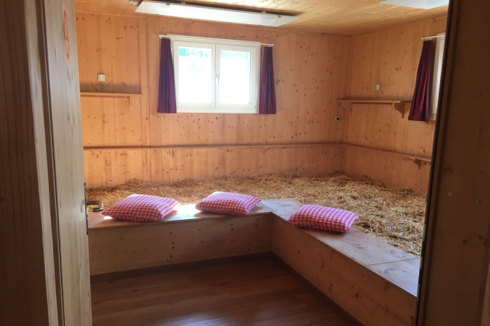 Schlafen im Stroh auf dem Hof Tossa weckt Erinnerungen an Ferien auf dem Bauernhof und Klassenlager in den Bergen (Foto: © Familie Höllrigl) Schlafraum mit Stroh und rot-weiss karierten Kissen im B&B Tossa Hof, Avers