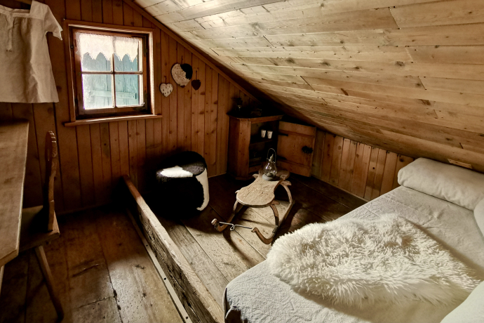 Nostalgico e sognante: Nella Berghaus Heimeli a Sapün, gli ospiti dormono tra mura di 300 anni (Foto: © Heimeli Swiss AG) Camera rustica alla Berghaus Heimeli a Sapün con scricchiolanti assi di legno, antichi mobili contadini grigionesi e un’atmosfera accogliente