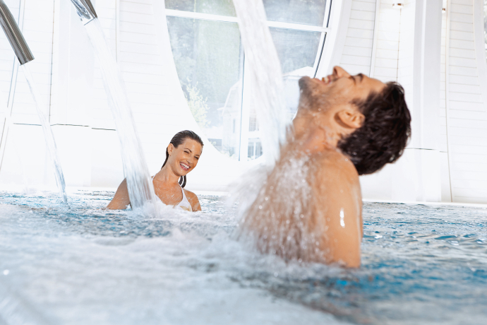 Tamina Therme im Grand Resort Bad Ragaz – Thermalwasser aus der Taminaschlucht, eingebettet in moderne Architektur (Foto: © Grand Resort Bad Ragaz) Junges Paar entspannt unter Massagedüsen in der Tamina Therme im Grand Resort Bad Ragaz