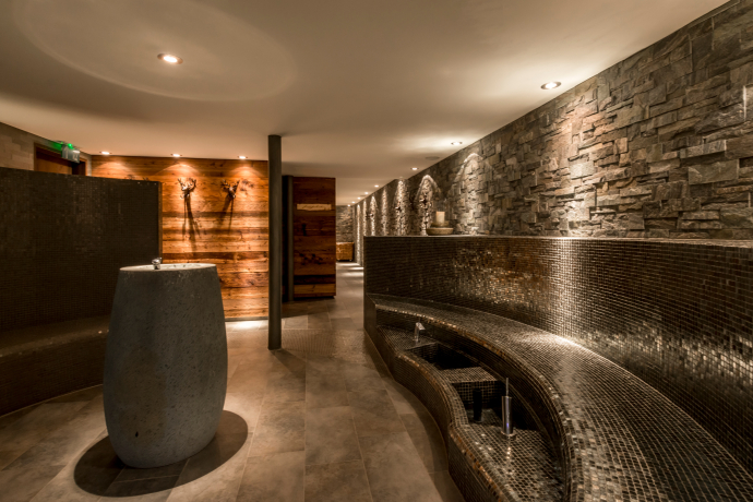 Spa de montagne à l'hôtel La Val Hotel & Spa Brigels – ambiance alpine avec des matériaux naturels pour une détente bienfaisante (Photo : © La Val Hotel & Spa) Spa de montagne à l'hôtel La Val Hotel & Spa Brigels avec des murs en pierre naturelle et un éclairage élégant