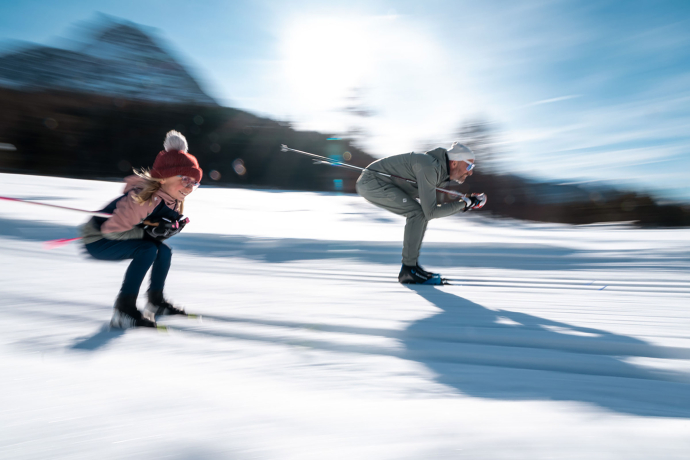 Abfahrt auf einer klassischen Loipe (Foto: © Filip Zuan) Ein Mann und ein Mädchen rasen die klassische Loipe hinunter.