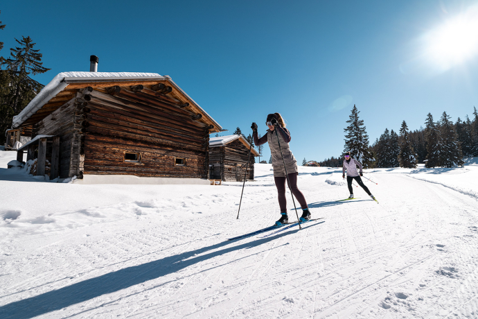 Langlaufende auf einer Loipe vor einem Stall in der Lenzerheide (Foto: © Filip Zuan) Zwei Langlaufende auf einer Loipe, welche vor einem Stall vorbei führt.
