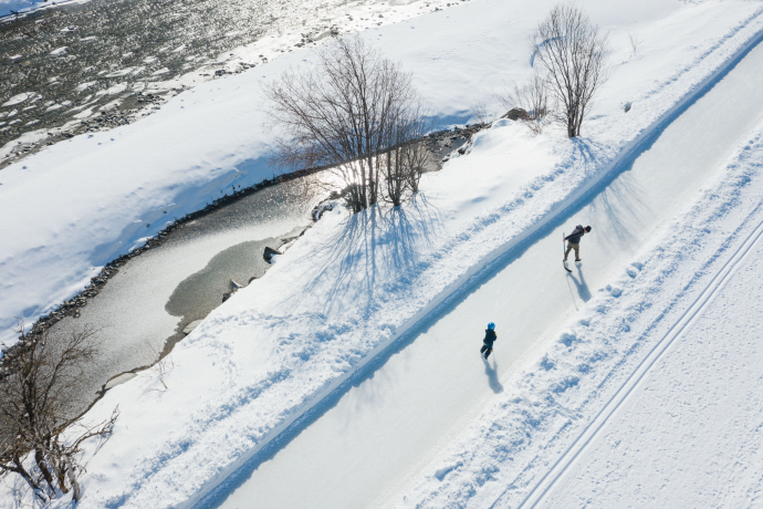 Glide by glide through unspoilt nature along the Inn (Photo: © Engadin Tourismus AG) Two people ice skating on the Ice Trail Madulain–Zuoz along the River Inn