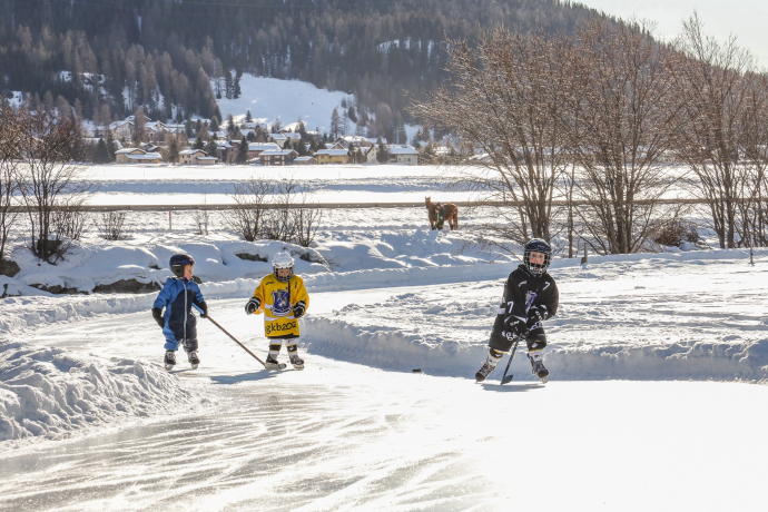 A spontaneous game of ice hockey between Madulain and Zuoz – there’s plenty of space for that too on the ice trail along the River Inn (Photo: © Engadin Tourismus AG) Three children playing ice hockey on the Ice Trail Madulain–Zuoz