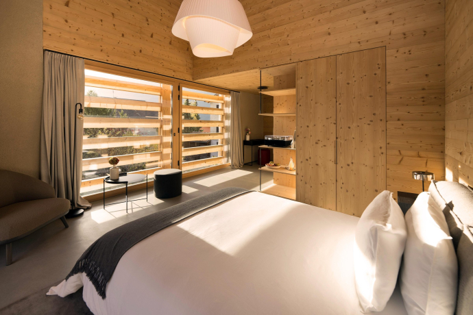 Chambre confortable de la Casa Giovanoli avec des parois en bois et vue sur le balcon ensoleillé