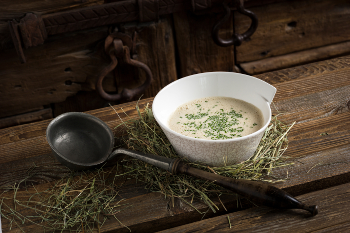 A bowl of Graubünden barley soup, presented rustically on hay