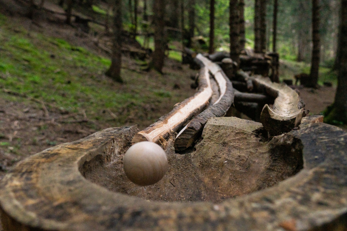 Metallkugel in einer Holzrinne eines Waldspielplatzes – La Bova bei Flims Laax.