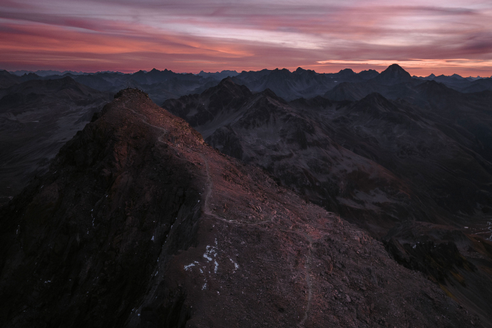 Dramatischer Herbst-Sonnenaufgang am Schwarzhorn mit leuchtend rosafarbenem Himmel und schneebedeckten Berggipfeln.