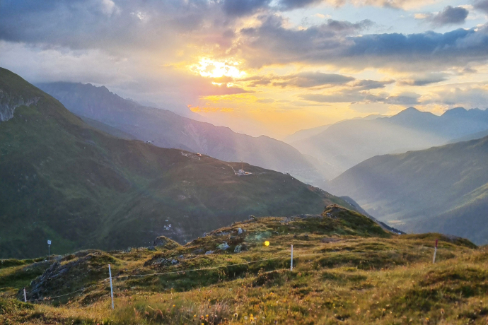 Sonnenaufgang über Disentis-Sedrun mit dem Piz Calmut, Alpentälern und goldenen Wiesen in der Berglandschaft.