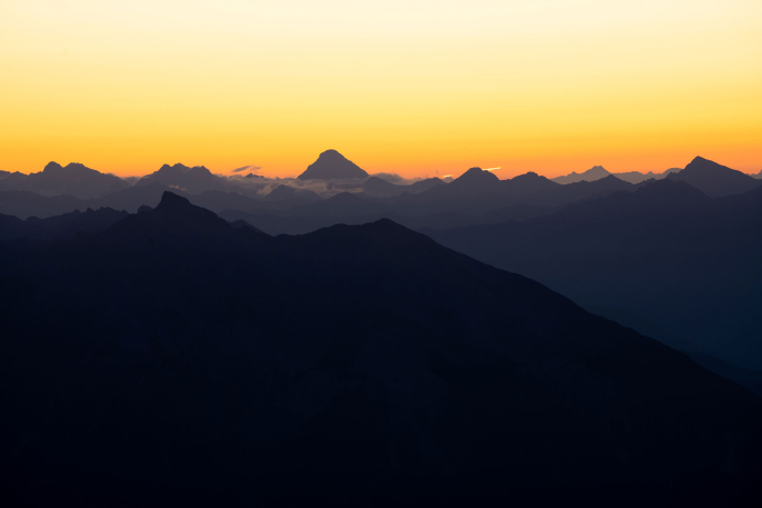 Sonnenaufgang über dem Piz Beverin in der Viamala. Bei goldenem Licht sieht man die Silhouette der Berge.