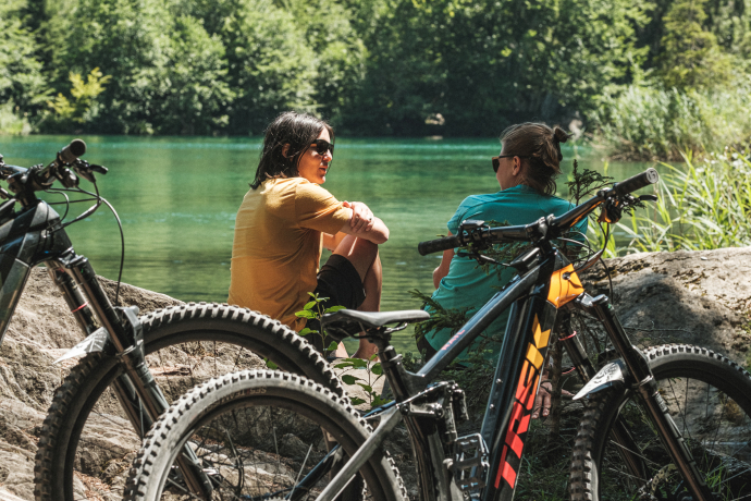 Zwei Mountainbiker machen eine Pause am Ufer des Caumasees in Flims Laax