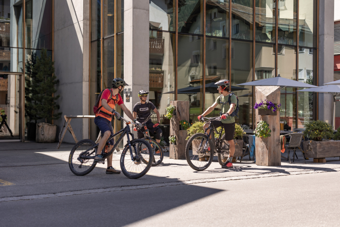 Mountainbiker vor dem ALL IN ONE HOTEL INN LODGE in Celerina, einem idealen Ausgangsort für die Corviglia Flow Trails