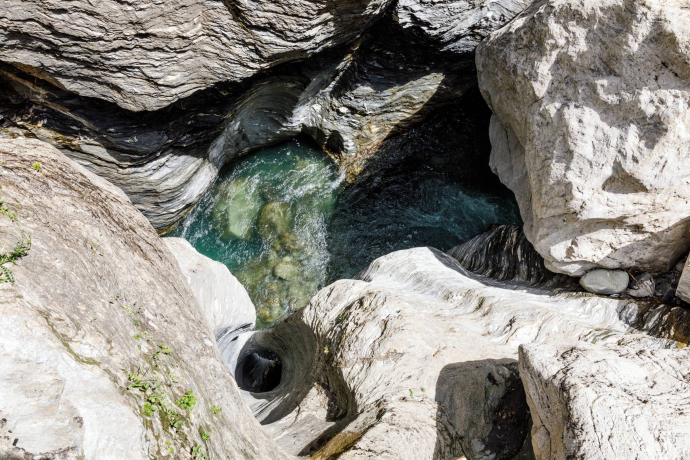 Türkisfarbenes Wasser fliesst durch glatt geschliffene Felsen und natürliche Strudeltöpfe in der Viamala-Schlucht.