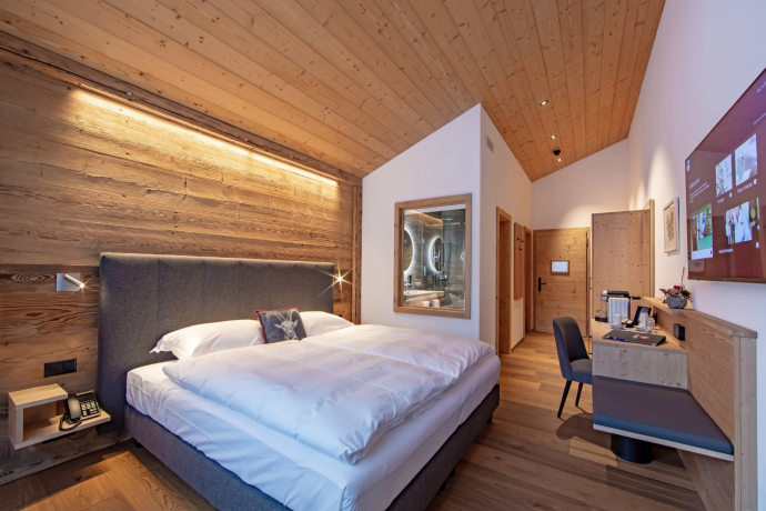 Moderna camera doppia all’Hotel Lengmatta con pareti e soffitto in legno, letto grande, area salotto, scrivania e bagno integrato.