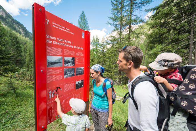 Auf dem Bahnerlebnisweg Albula erleben Sie das perfekte Zusammenspiel von Landschaft und Technik (Foto: © Rhätische Bahn / Mattias Nutt) Eine Familie studiert eine Tafel auf dem Bahnerlebnisweg Albula