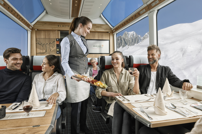 Durante il viaggio sul Glacier Express vengono serviti piatti preparati al momento (Foto: © Glacier Express AG / Stefan Schlumpf) Un addetto del treno serve un piatto freddo sul Glacier Express