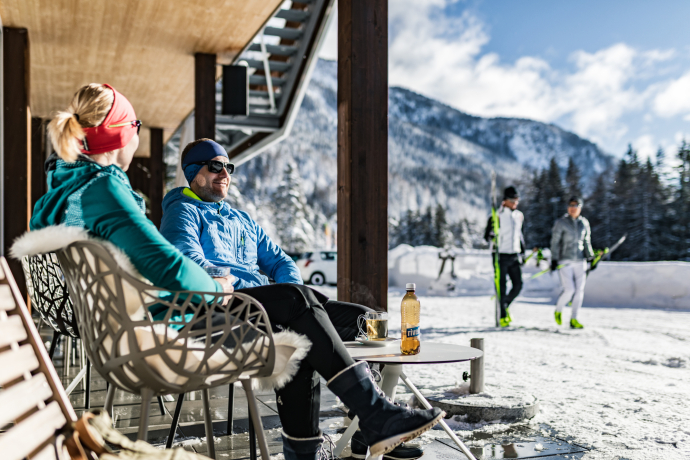Frische Bergluft und Sonne tanken Ein Paar entspannt vor der Biathlon Arena Lenzerheide