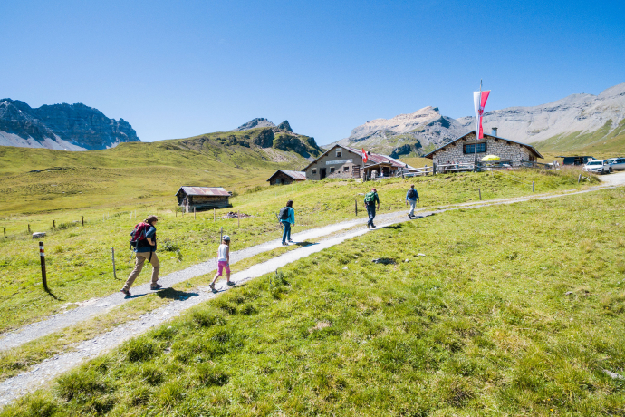 Blick auf die Alp Nurdagn, umgeben von saftigen Wiesen und imposanten Berggipfeln
