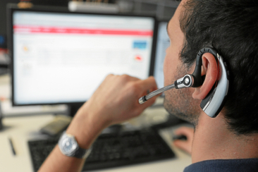 Ein Mann mit einem Headset blickt auf einen Bildschirm