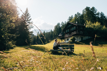 Bloggerin Katharina Werni liest auf einer Bank vor dem Hof Zuort in einem Buch