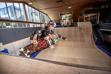 Skateboarder fährt auf einer Halfpipe in der Freestyle Academy