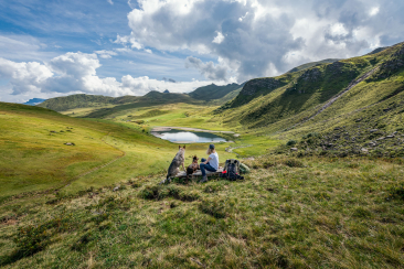 Eine Wanderin geniesst zusammen mit zwei Hunden die Ruhe und Aussicht in den Fideriser Heubergen