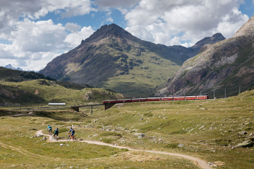 Mountainbiker fahren entlang der Bahnlinie mit dem Bernina Express