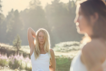 Zwei Frauen weiss gekleidete Frauen dehnen ihre Arme für eine Yoga-Session