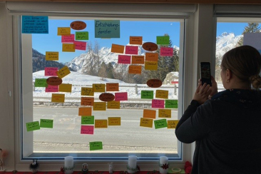 Workshop-Teilnehmende kleben Post-Its auf Fensterscheibe