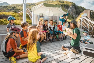 Eine Frau zeigt Kindern im Arosa Bärenland einen Bärenschädel
