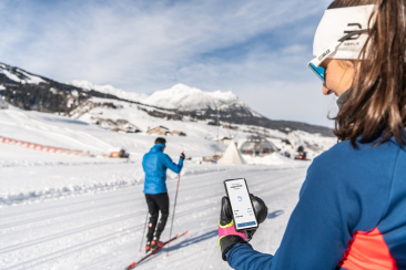 Eine junge Frau beim Langlaufen, während sie die App «Alle laufen lang» auf ihrem Smartphone benutzt