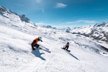 Zwei Wintersportler geniessen das Frühlingsskifahren auf einer sonnigen Piste im Engadiner Skigebiet Corvatsch