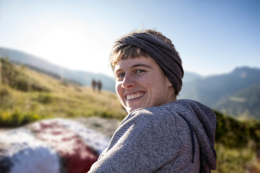 Porträt der Wanderleiterin Fabienne Kaufmann mit Blick in die Kamera, im Hintergrund eine sommerliche Berglandschaft