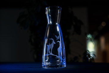 Glaskaraffe mit Steinbock-Motiv auf dunklem Hintergrund