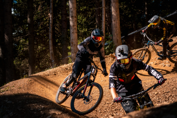 3 Biker*innen im Trail.