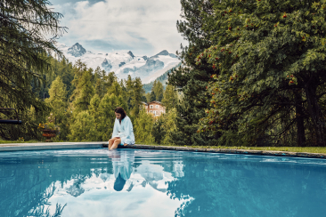 Frau im Bademantel am Aussenpool des Hotel Saratz mit Blick auf Gletscher und Piz Glüschaint