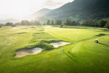 Golfspieler auf dem Golfplatz Buna Vista in Sagogn mit Blick auf das sonnenbeschienene Tal und umliegende Berge