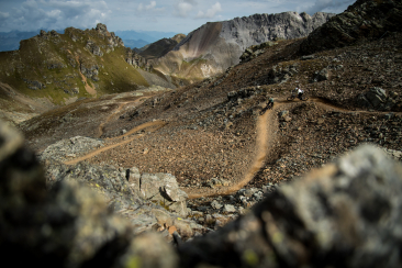 Zwei Mountainbiker fahren auf einem kurvigen Trail durch felsige Berglandschaft im Bike Kingdom Lenzerheide