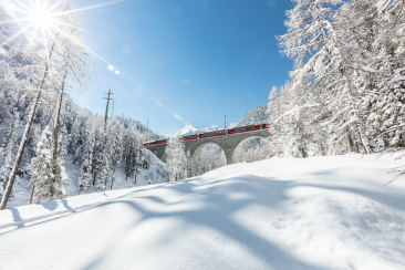 Bernina Express auf dem Albulaviadukt in tief verschneiter Winterlandschaft