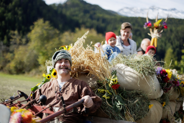 Festlich geschmückter Umzugswagen mit Teilnehmern am Erntedankfest in der Val Müstair