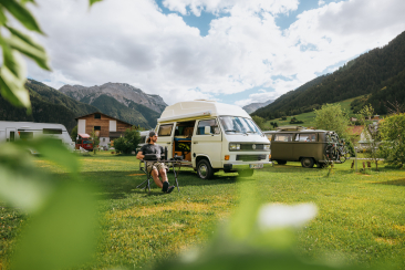 Camping Muglin in Müstair mit Camper und VW-Bus vor Bergkulisse
