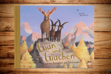 Buchcover des Kinderbuchs «Gian & Giachen und der Platzhirsch vom Lärchenwald»: Zwei Steinböcke stehen neben dem stolzen Hirsch Jori auf einem Felsen im herbstlichen Lärchenwald