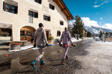 Langläufer mit Ski laufen durch das Dorf Celerina im Oberengadin
