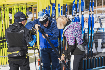 Ski-Service am Teststand: Drei Personen pruefen Langlaufskier und Belag.