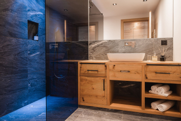Modernes Badezimmer der Avero Lodge in Samnaun mit Walk-In-Dusche und Holz-Waschtisch
