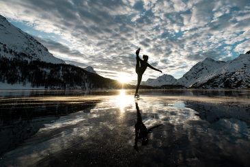 Patineuse artistique sur le lac de Sils gelé au coucher du soleil