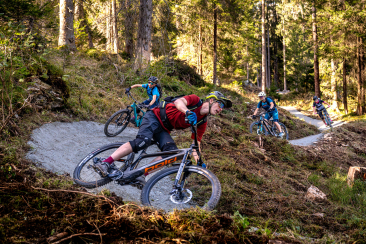 Bikende auf dem Foppa Trail in Flims Laax umgeben von einer schönen Waldlandschaft.