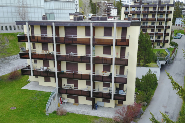 Mehrgeschossiges Wohnhaus mit Balkonen und geschlossenen Fensterläden